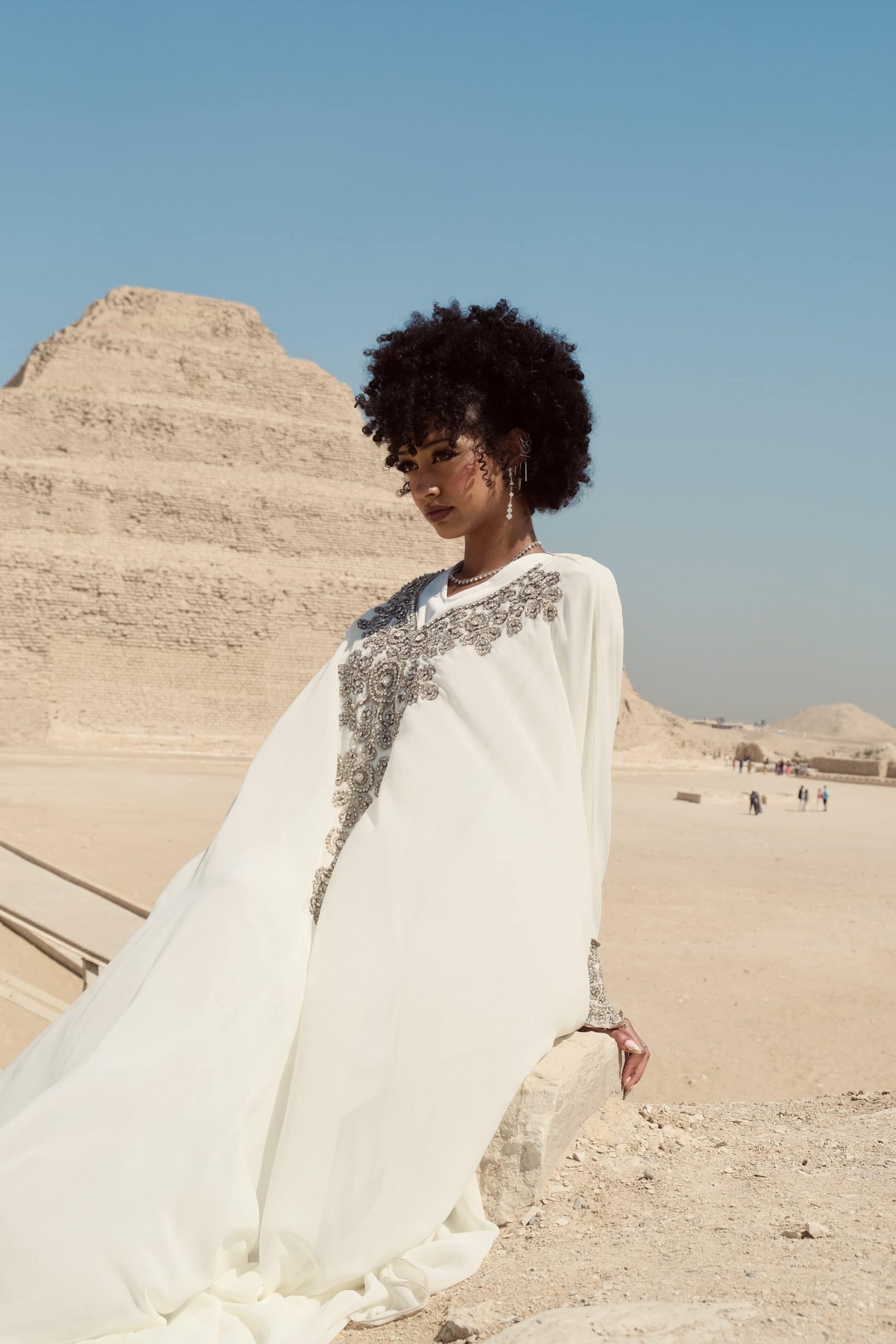 Spiritual Lady at Saqqara Beautiful lady in white dress sits in front of the stepped pyramid of Saqqara