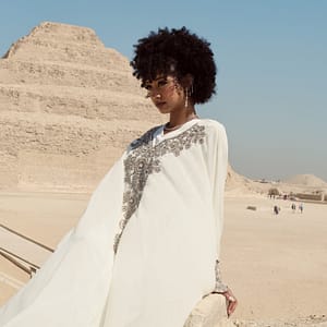 Beautiful lady in white dress sits in front of the stepped pyramid of Saqqara